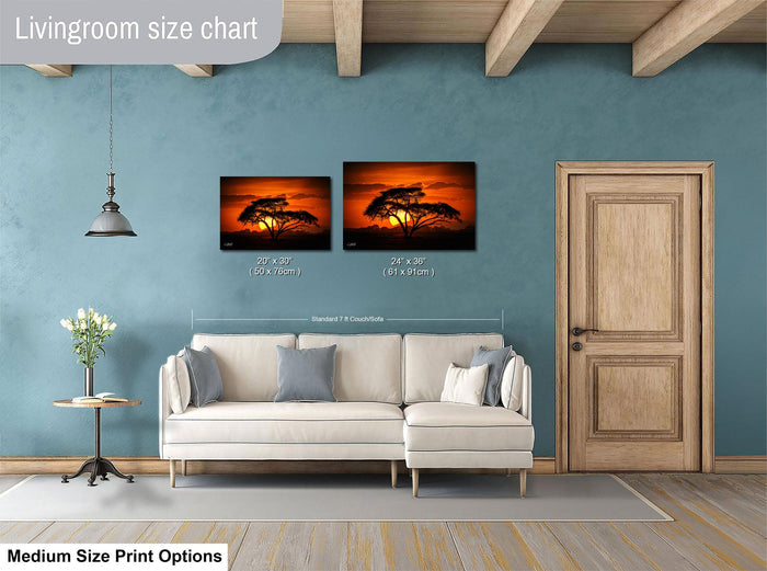 a living room with a white sofa, a wooden door, and a painting of a sunset on the wall. The painting is of a tree with a warm, orange sky. The living room appears to be well-lit and decorated, with a potted plant and a vase adding to the ambiance.