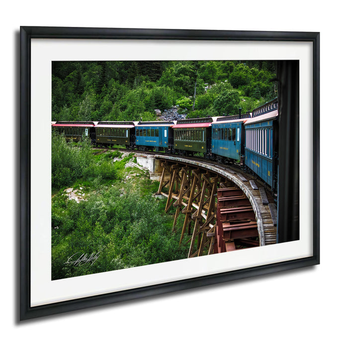 A vintage train traveling on a curved track through a lush, green forest.