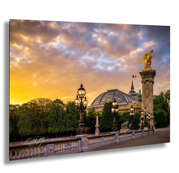 a grand, ornate building with a golden eagle statue atop a tall column, set against a vibrant sunset sky.