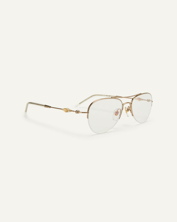 Quarter shot of Bonnie Clyde Autobio aviator optical frames in gold with clear lenses.