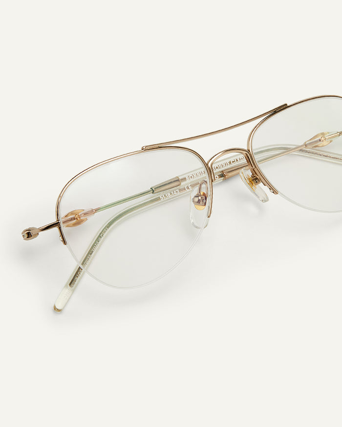Side shot of Bonnie Clyde Autobio aviator optical frames in gold with clear lenses.