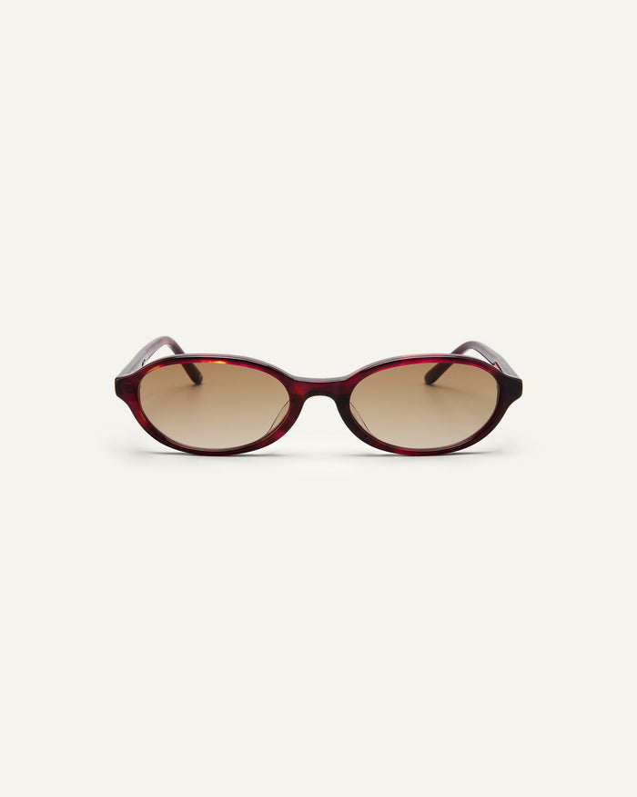 Face shot of Bonnie Clyde Baby oval sunglasses in red tortoise with brown gradient lenses.