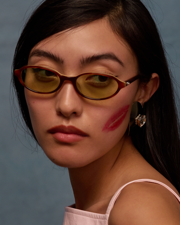Quarter shot of Bonnie Clyde Baby oval sunglasses in layered brown with green lenses.