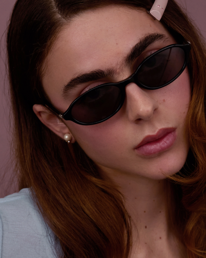 Quarter shot of Bonnie Clyde Baby oval sunglasses in black with black lenses.