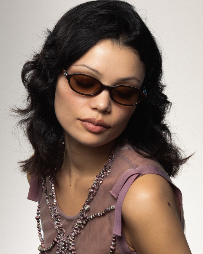 Quarter shot of Bonnie Clyde Baby oval sunglasses in layered teal demi with brown gradient lenses.