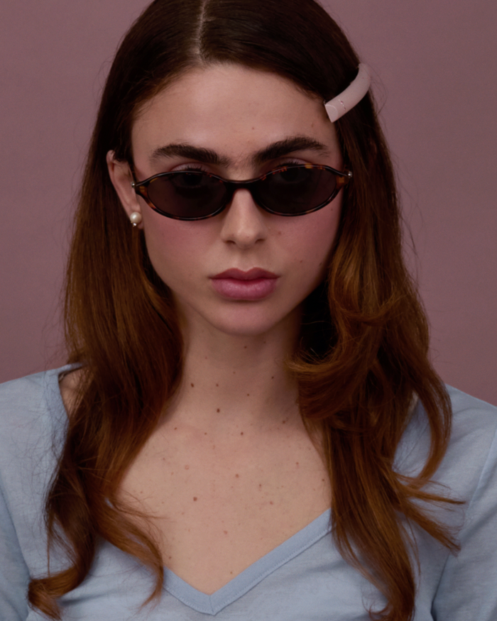Quarter shot of Bonnie Clyde Baby oval sunglasses in tortoise with black lenses.