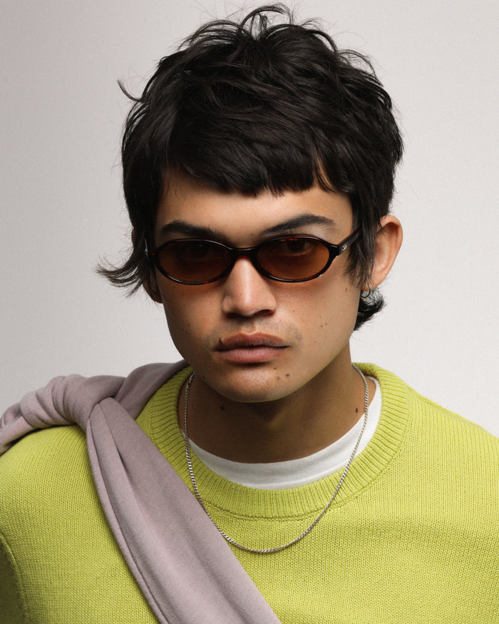Quarter shot of Bonnie Clyde Baby oval sunglasses in red tortoise with brown gradient lenses.
