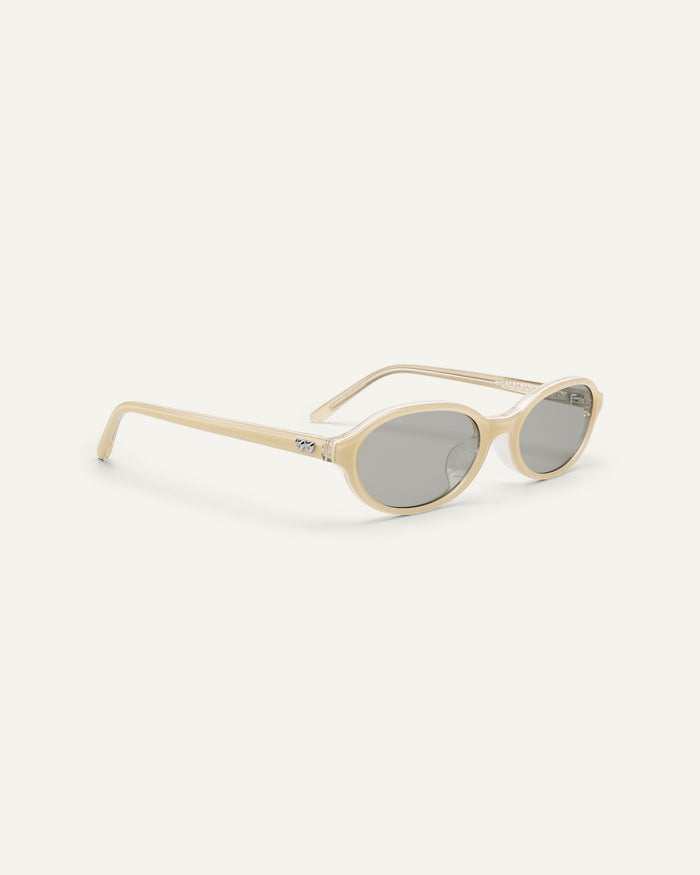 Side shot of Bonnie Clyde Baby oval sunglasses in layered off white with grey lenses.