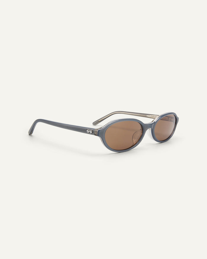 Side shot of Bonnie Clyde Baby oval sunglasses in layered silver with brown lenses.