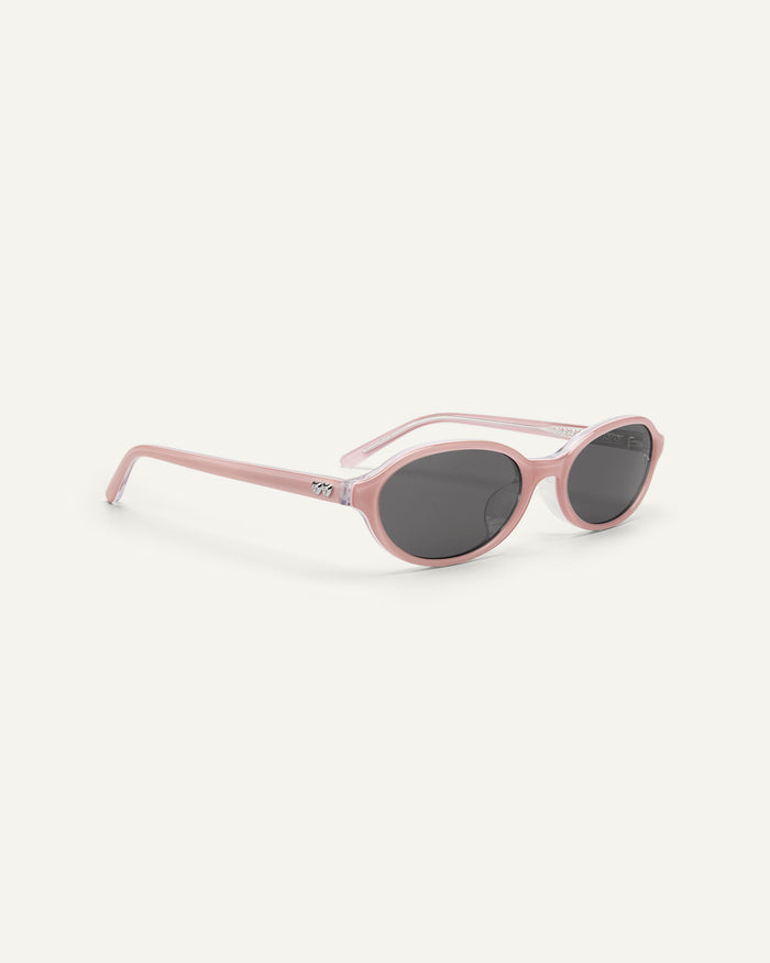 Side shot of Bonnie Clyde Baby oval sunglasses in layered pink with black lenses.