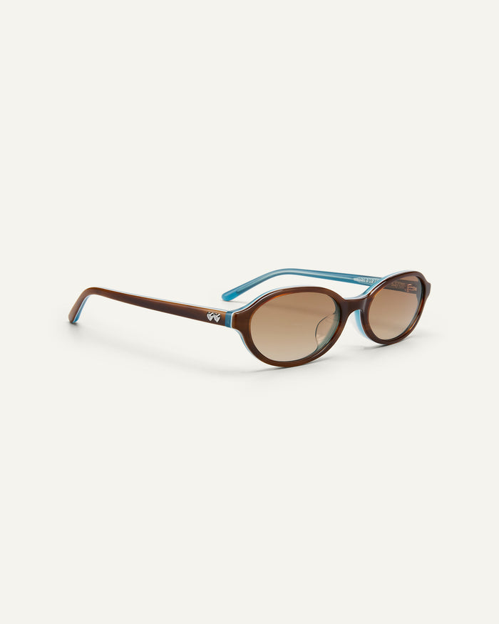 Side shot of Bonnie Clyde Baby oval sunglasses in layered teal demi with brown gradient lenses.