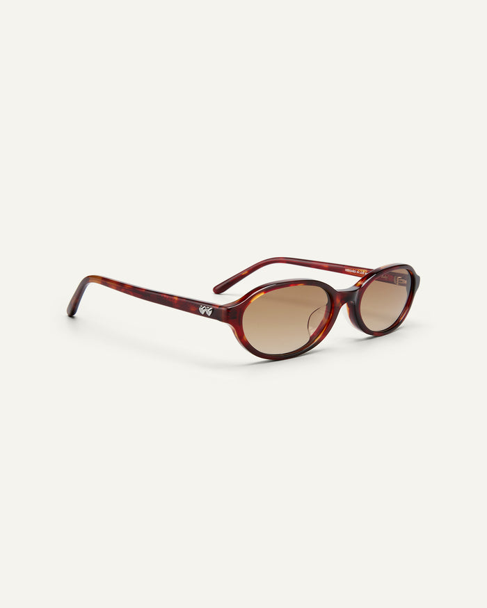 Side shot of Bonnie Clyde Baby oval sunglasses in red tortoise with brown gradient lenses.
