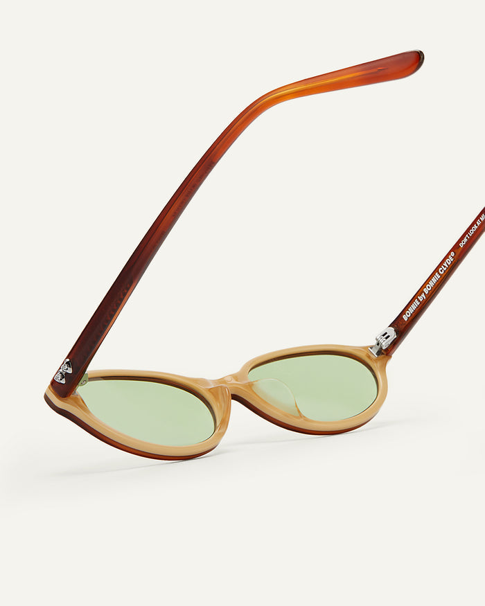 Close-up shot of Bonnie Clyde Baby oval sunglasses in layered brown with green lenses.