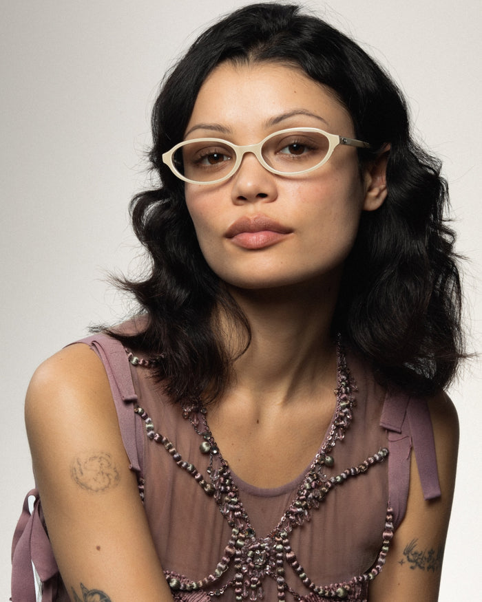 Close-up shot of Bonnie Clyde Baby oval optical frames in layered off white with clear lenses.