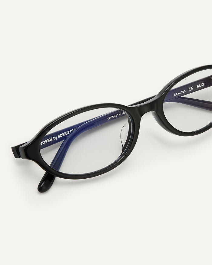 Close-up shot of Bonnie Clyde Baby oval optical frames in black with clear lenses.