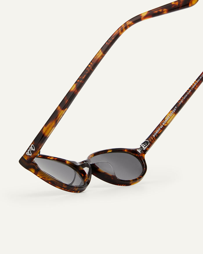 Close-up shot of Bonnie Clyde Baby oval sunglasses in tortoise with black lenses.