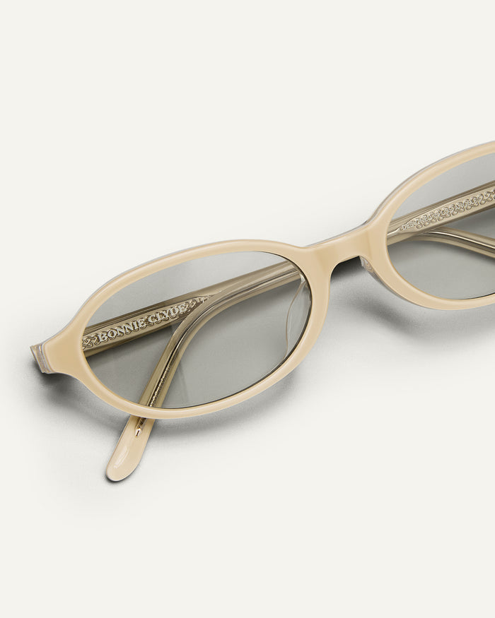 Close-up shot of Bonnie Clyde Baby oval sunglasses in layered off white with grey lenses.