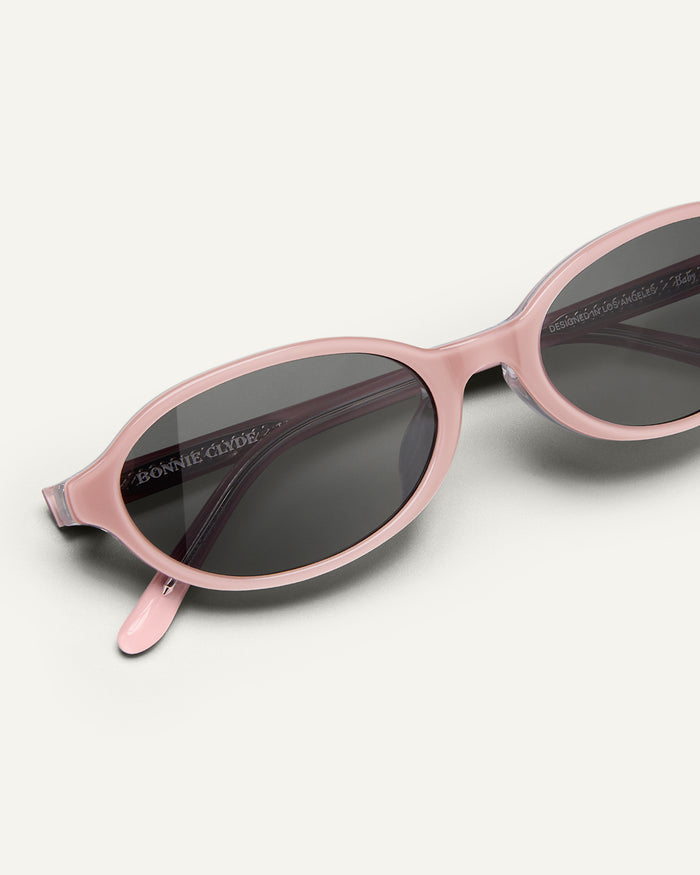 Detail shot of Bonnie Clyde Baby oval sunglasses in layered pink with black lenses.