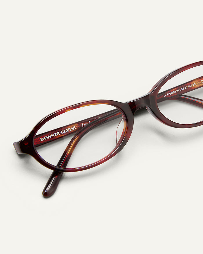 Detail shot of Bonnie Clyde Baby oval optical frames in red tortoise with clear lenses.
