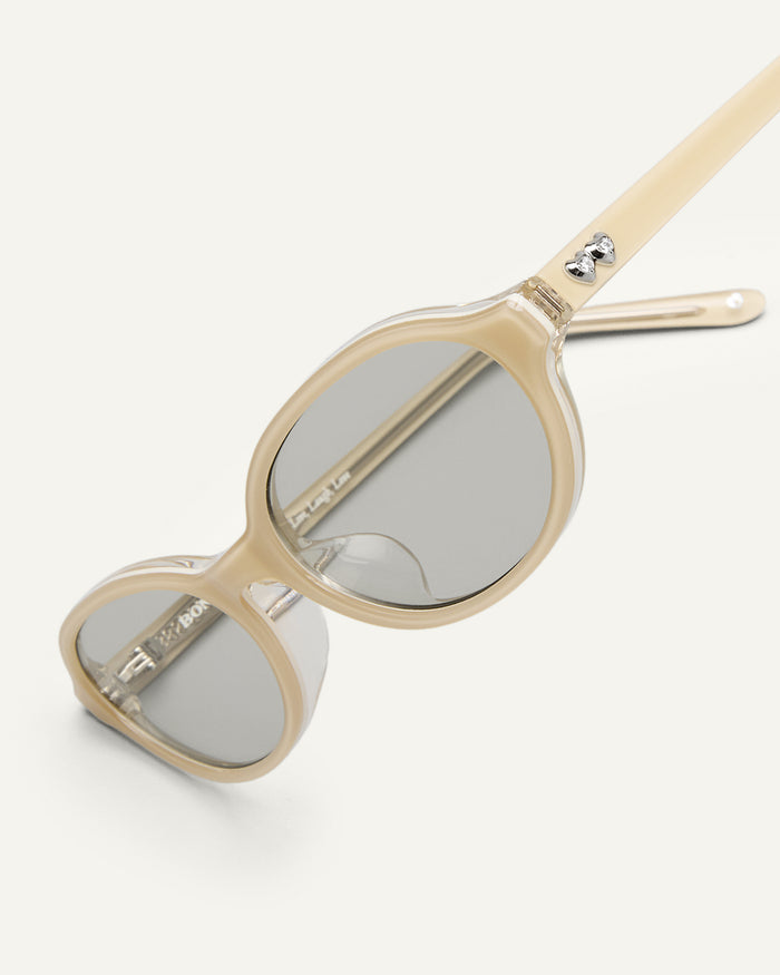 Detail shot of Bonnie Clyde Baby oval sunglasses in layered off white with grey lenses.