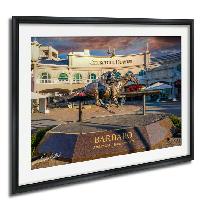 A bronze statue of a horse and jockey racing on a track, with the name "Barbaro" inscribed on a pedestal in front of the building.