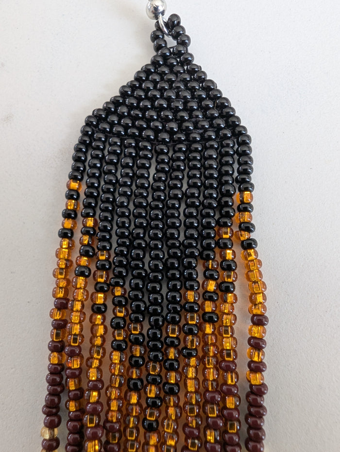 Beaded earring with black, brown, and gold beads on a white background