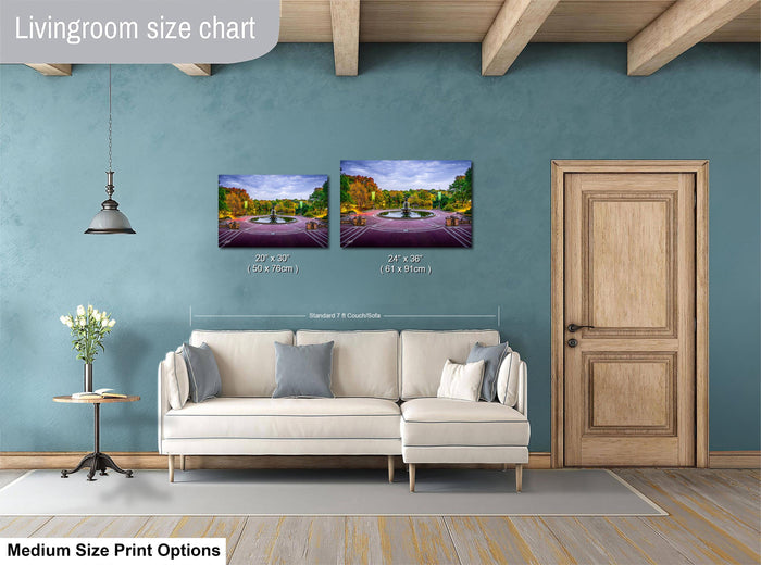 a living room with a white sofa, a wooden door, and a painting of a park scene on the wall. The painting is of a fountain and trees, and it is labeled as a medium-sized print.