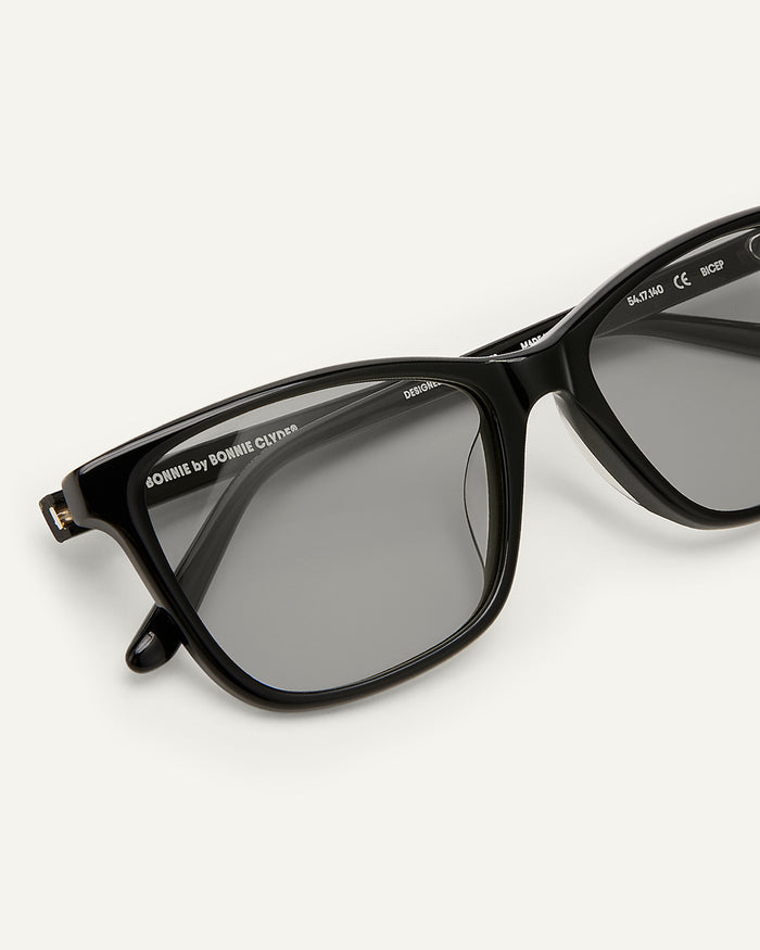 Side shot of Bonnie Clyde Bicep sunglasses in black with grey lenses.