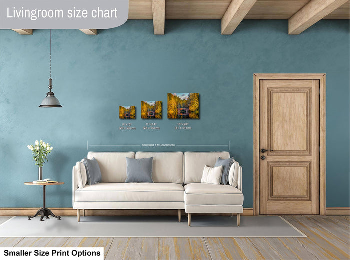 a living room with a white sofa, a wooden door, and a hanging light fixture. There are three framed pictures of different sizes displayed on the wall above the sofa.