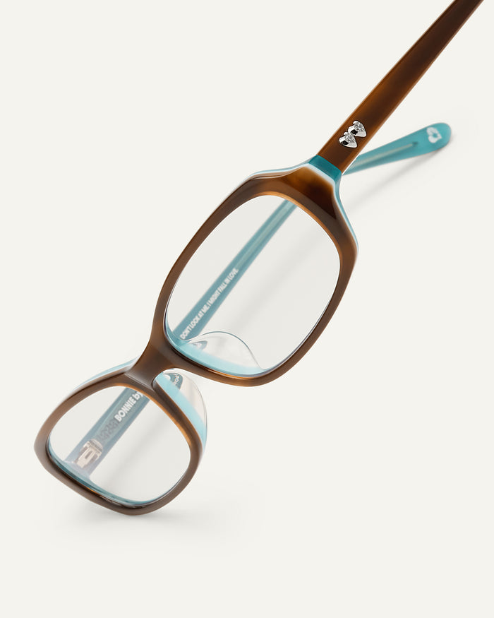 Detail shot of Bonnie Clyde Blondie optical frames in layered teal demi with clear lenses.