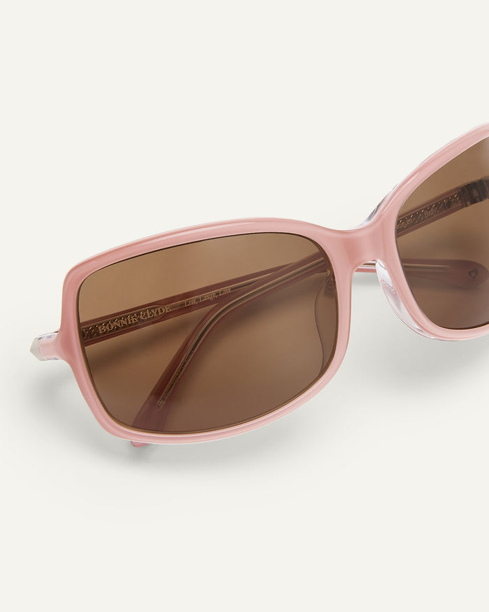 Detail shot of Bonnie Clyde Body rounded square sunglasses in layered pink with brown lenses.