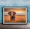 A large elephant stands in a grassy field, with two smaller lions in the background, against a backdrop of a blue sky with clouds.