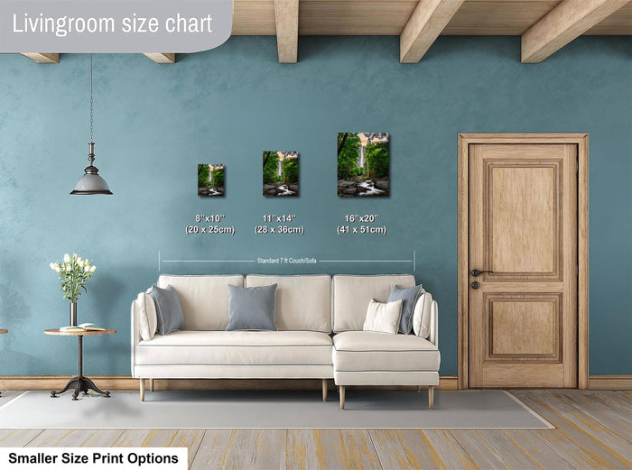 a living room with a white sofa, a wooden door, and a hanging light fixture. There are three framed pictures of nature scenes displayed on the wall, each with a different size and height. The wall is painted in a light blue color, and the floor is covered with a gray rug.