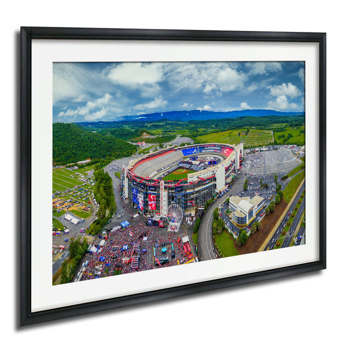 The image is an aerial view of a large stadium surrounded by a large field, with a large crowd of people gathered in the area.