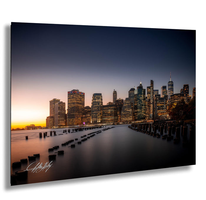 a city skyline at sunset, with tall buildings illuminated against a dark sky.