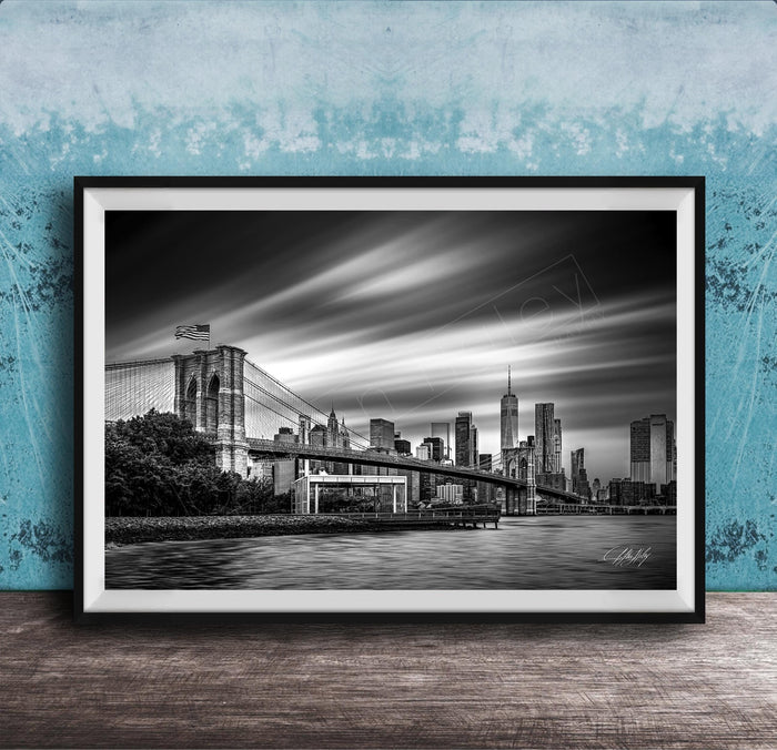 A black and white photograph of the Brooklyn Bridge in New York City, with the city skyline in the background.