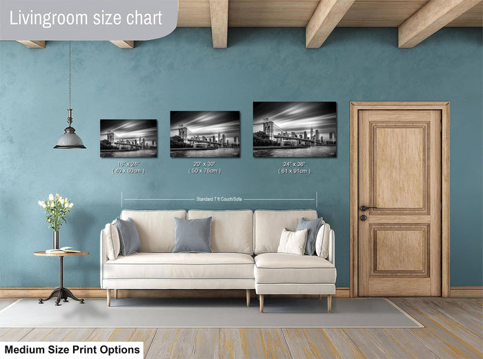 a living room with a white sofa and a wooden door. Above the sofa, there are three framed black and white photographs of cityscapes, each with a different size. The wall behind the sofa has a blue color, and there is a lamp hanging from the ceiling. The image also includes text that provides size information for the framed photographs.