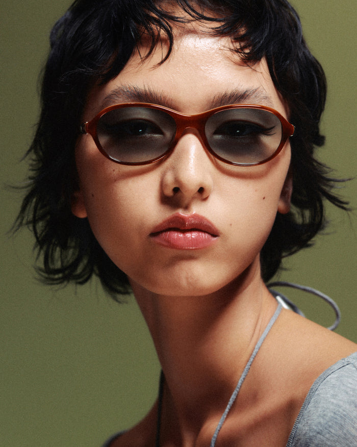Quarter shot of Bonnie Clyde Butter Knife sunglasses in layered brown with green lenses.