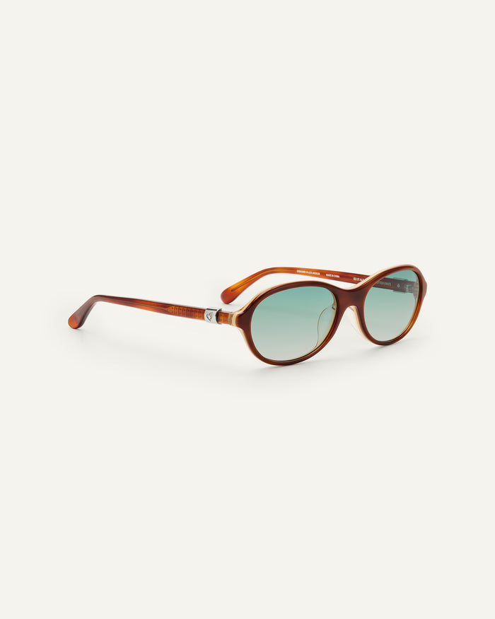 Close-up shot of Bonnie Clyde Butter Knife sunglasses in layered brown with green lenses.