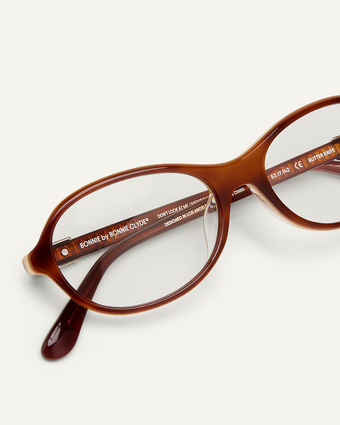 Detail shot of Bonnie Clyde Butter Knife optical frames in layered brown with clear lenses.
