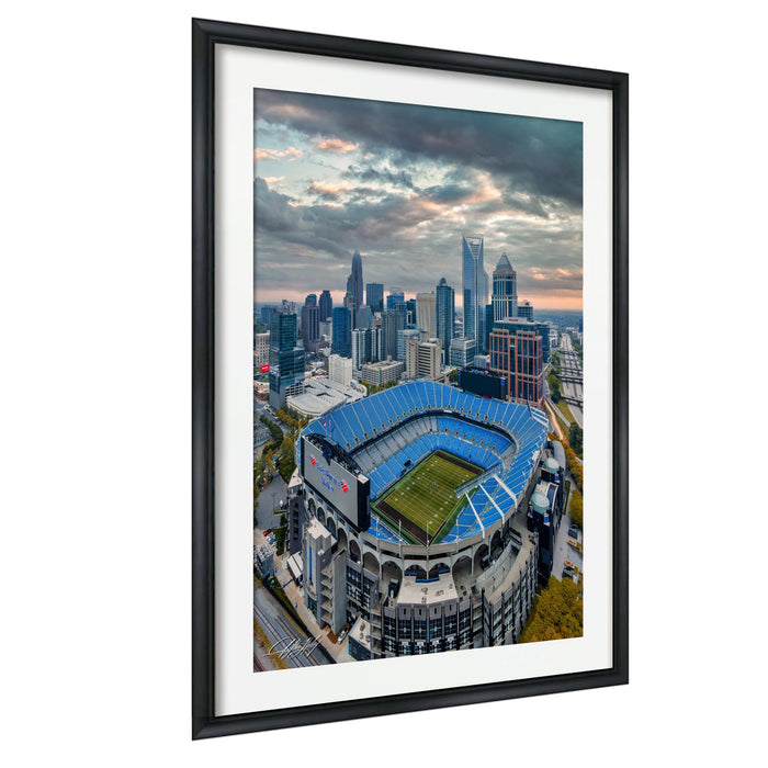 An aerial view of a large sports stadium with a city skyline in the background.