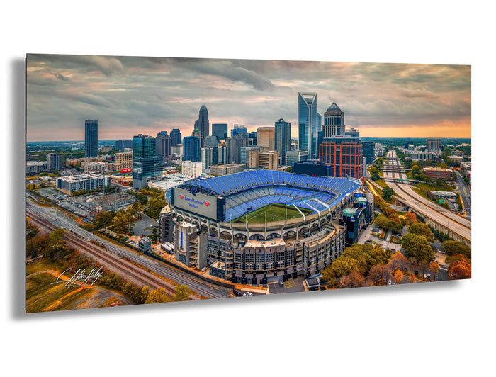 An aerial view of a large stadium with a blue roof, surrounded by a city skyline with tall buildings and skyscrapers.