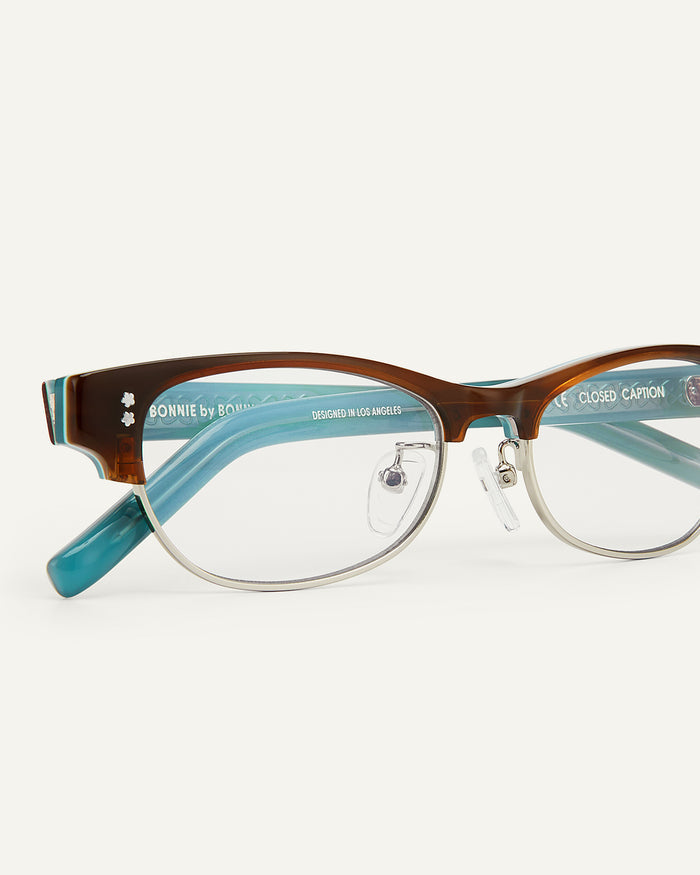 Close-up shot of Bonnie Clyde CC optical frames in layered demi teal with clear lenses.