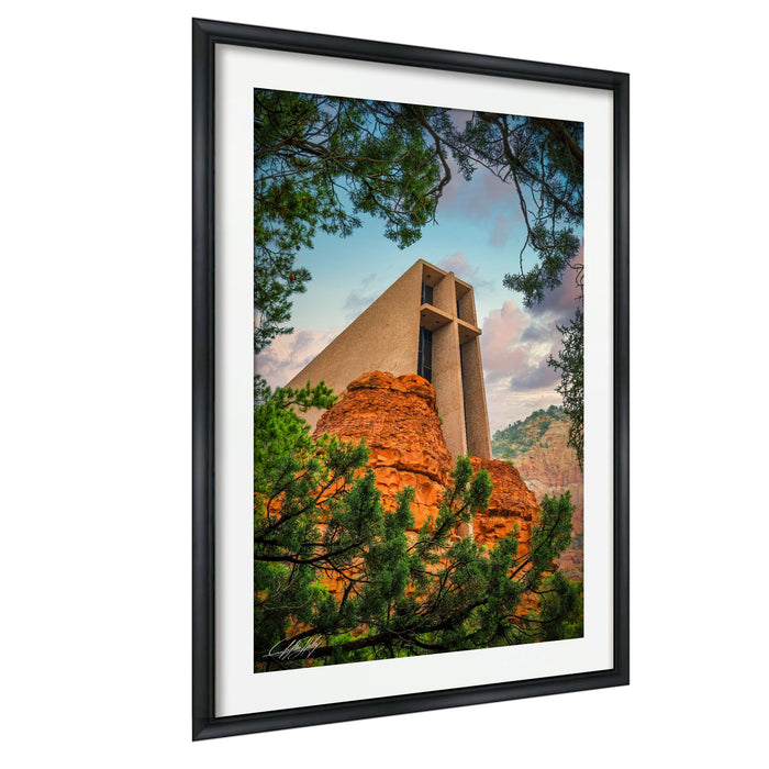 A framed photograph depicting a large, modern building with a distinctive architectural design, surrounded by lush greenery and a mountainous landscape.
