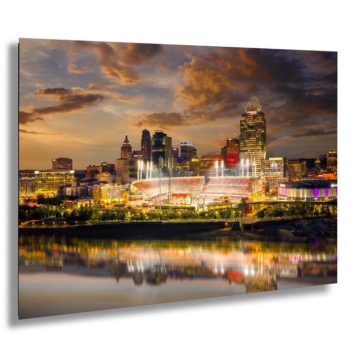 a city skyline at night, with a large stadium and other illuminated buildings reflected in the water below.