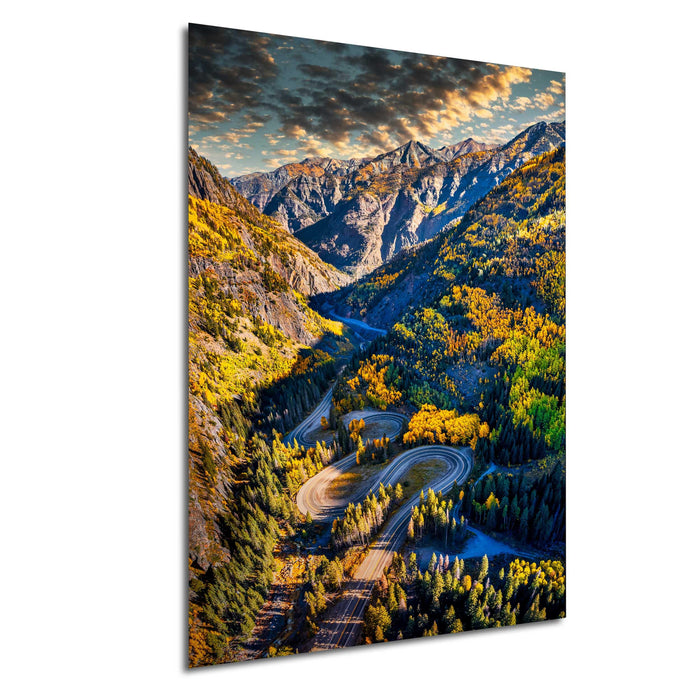 a winding road cutting through a mountainous landscape with vibrant autumn foliage.