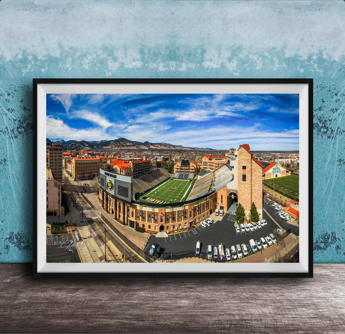 The image is a framed aerial view of a city, featuring a football stadium, buildings, and a parking lot.