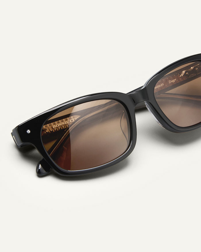 Detail shot of Bonnie Clyde Dagger sunglasses in black with brown lenses.
