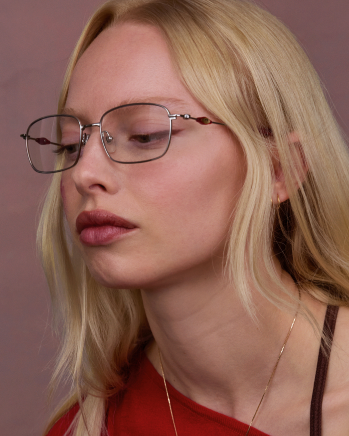 Quarter shot of Bonnie Clyde Dance Dance optical frames in silver and layered red with clear lenses.