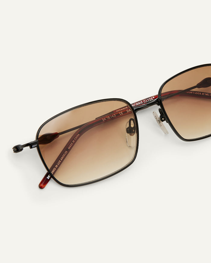 Close-up shot of Bonnie Clyde Dance Dance sunglasses in black and red tortoise with brown gradient lenses.